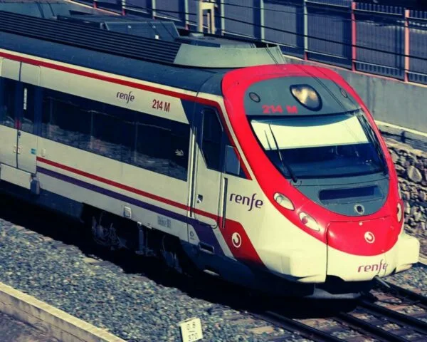 Modern train arriving at a station with clear blue skies in the background, showcasing efficient transportation